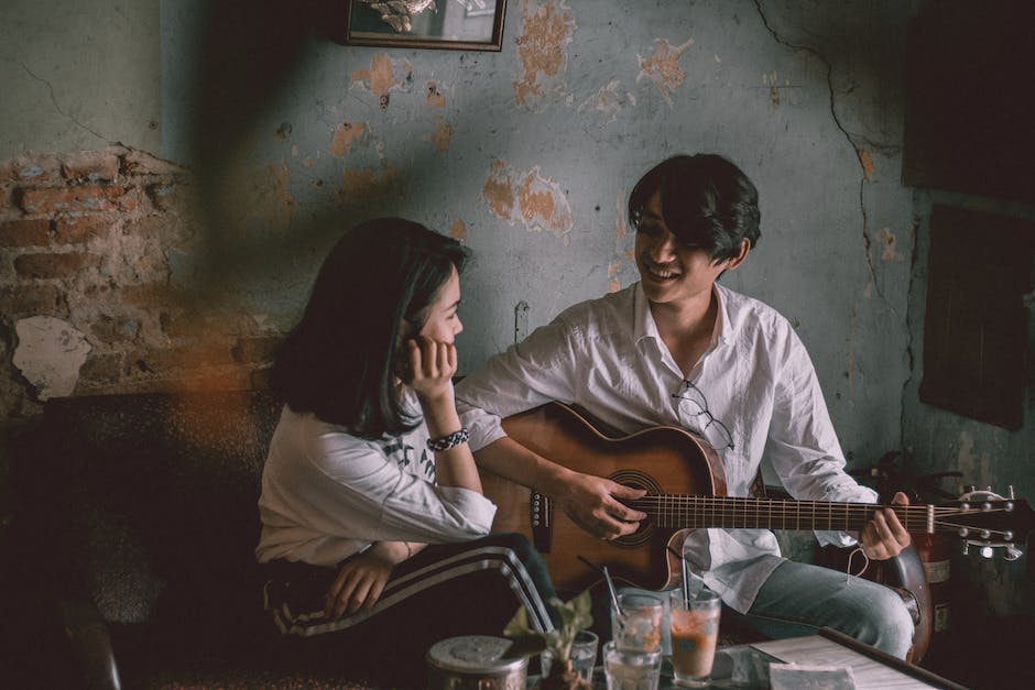 Image of a person playing a guitar and strumming the strings.